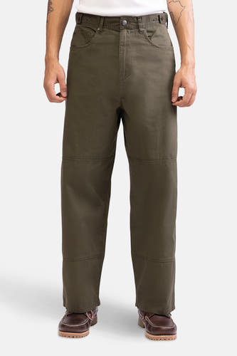 Pantalon vert de REDEFINED REBEL avec des renforts de genoux, porté avec des chaussures marron.
