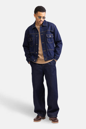 Jean en denim bleu marine large de REDEFINED REBEL, avec une coupe décontractée, associé à un pull marron et des chaussures marrons.