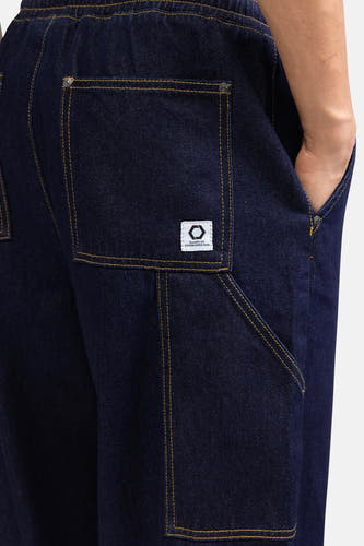 Jean denim bleu marine large de REDEFINED REBEL, avec des boutons et un étiquette blanche sur la poche arrière.