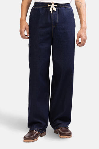 Jean denim bleu marine large de REDEFINED REBEL avec une ceinture élastique et des chaussures en cuir marron.