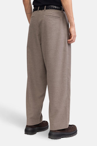 Persoon in wijde, bruine broek en bruine schoenen met dikke zool.