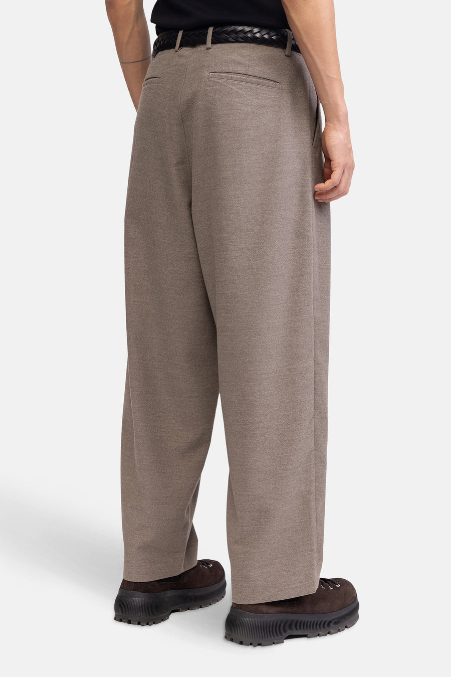 Persoon in wijde, bruine broek en bruine schoenen met dikke zool.