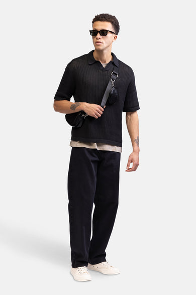 Jean noir décontracté de REDEFINED REBEL, avec une coupe décontractée et associé à un t-shirt tricoté noir et des baskets crème.