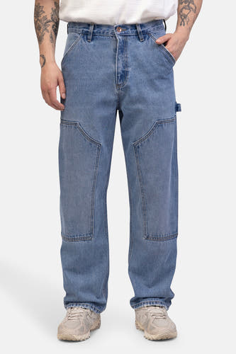 Jean décontracté de denim bleu clair de REDEFINED REBEL, avec des poches arrière et une poche à outils, et des baskets beige.