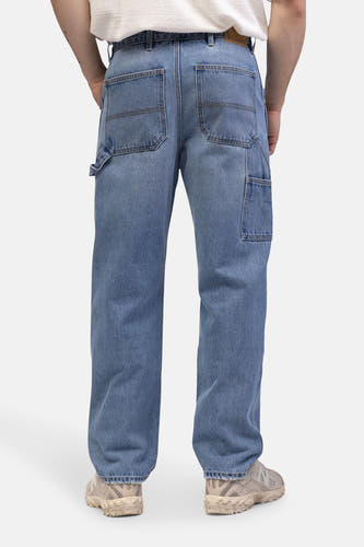Wijde jeans van lichtblauw denim van REDEFINED REBEL, met achterzakken en gereedschapszak, en beige sneakers.
