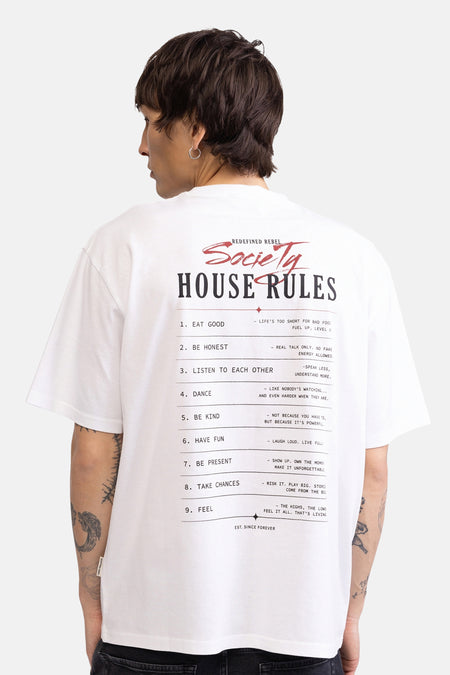 Wit T-shirt van REDEFINED REBEL met een grote grafische print 'Society House Rules' op de rug, gedragen door een man met tatoeages.