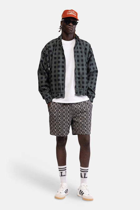 T-shirt blanc de REDEFINED REBEL, stylé décontracté sous une veste à carreaux zippée, avec short et baskets.