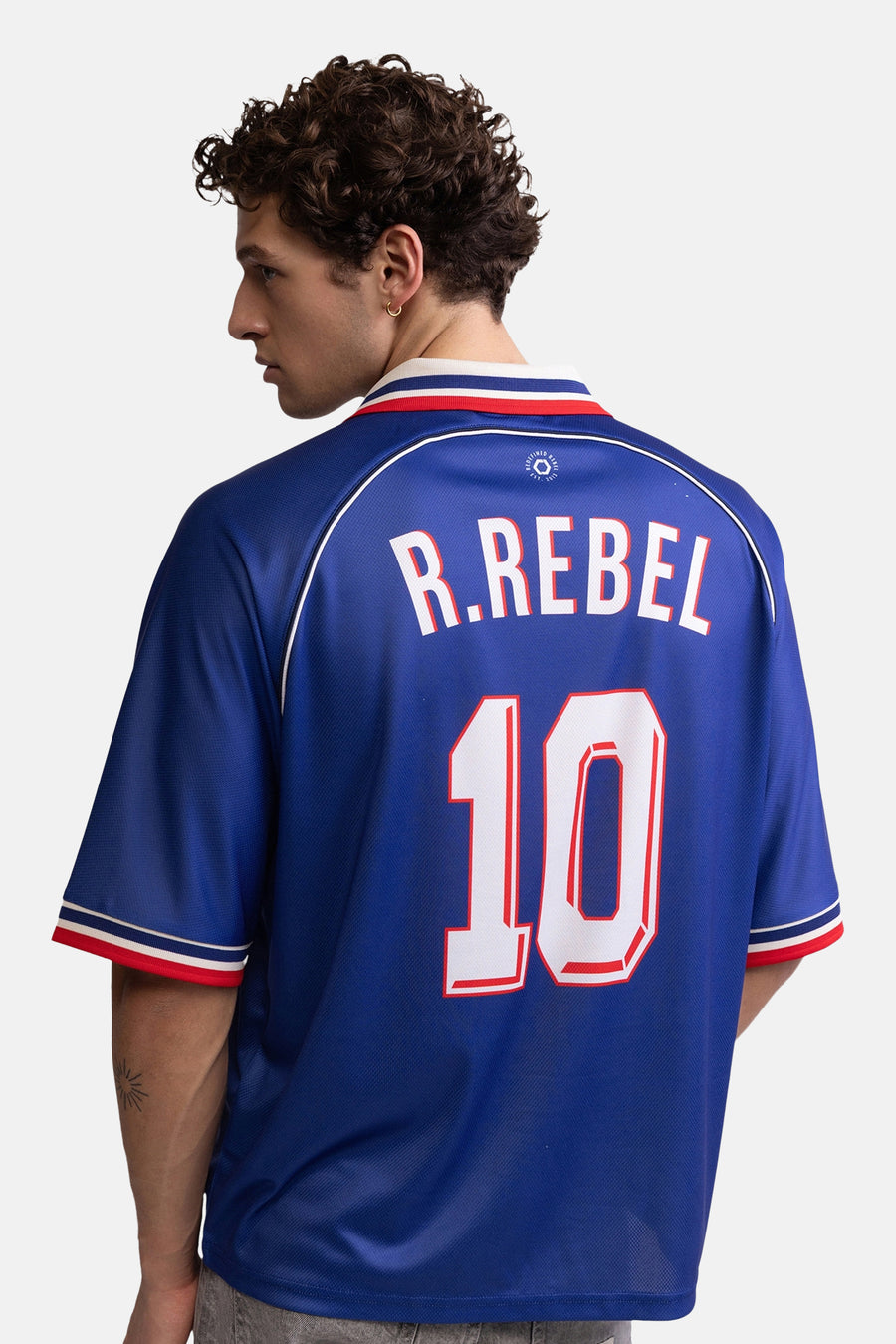 Blauwe polo met witte en rode accenten van REDEFINED REBEL, rugzijde met R.REBEL en nummer 10, mesh stof, model van achteren