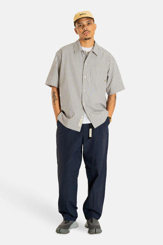 Chemise rayée grise de WOODBIRD à manches courtes, avec un col ouvert et portée avec un pantalon foncé.