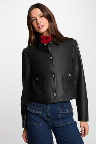 Manteau court noir de Morgan De Toi avec fermeture à boutons, poches et associé à un gilet rouge et des jeans.