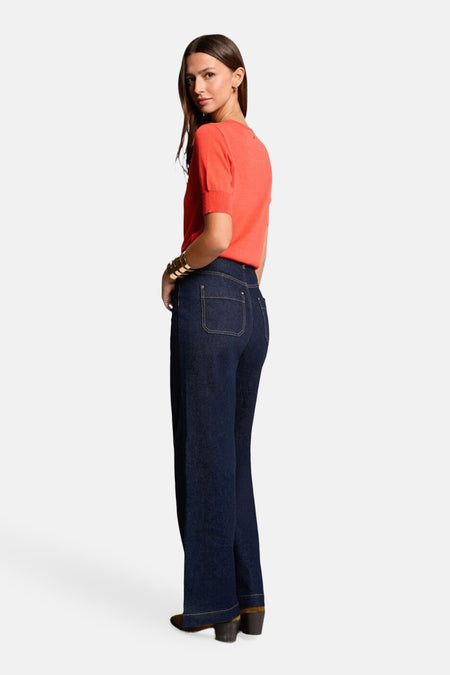 Maillot orange avec col rond de Morgan De Toi, associé à des jeans noirs et un bracelet doré.