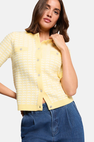 Cardigan bleu Morgan Morgan De Toi avec un motif à carreaux blancs et des boutons décoratifs, porté avec des bijoux argentés.