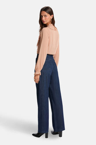 Beige blouse met lange mouwen van Morgan De Toi, met ruches op de hals en gedragen met donkere jeans.
