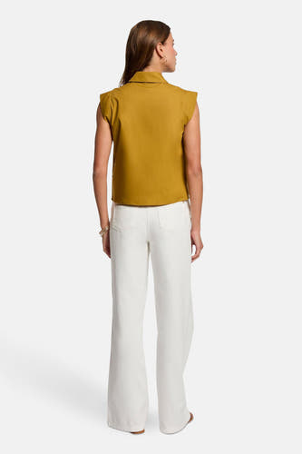 T-shirt jaune sans manches de Morgan De Toi, avec col et associé à un pantalon blanc.
