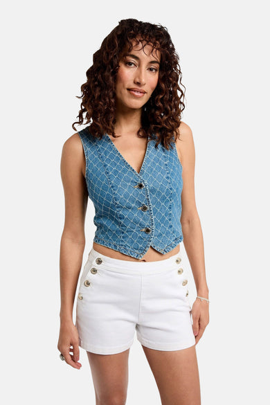 Blazer en denim bleu de Morgan De Toi, avec fermeture à boutons et motif carreaux sur toute la surface, associé à des short blancs avec des boutons dorés.