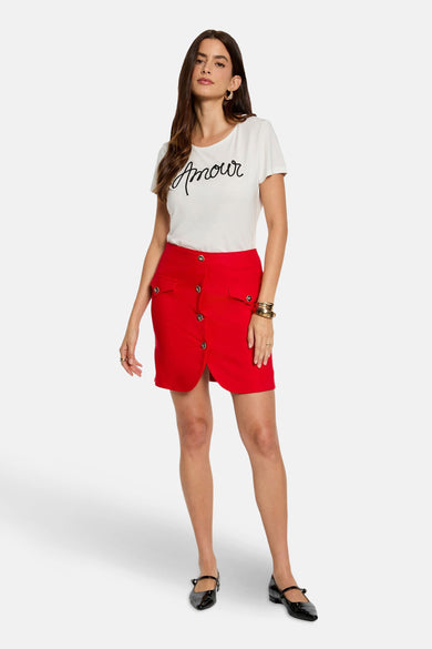 Blouse blanche de Morgan De Toi, avec une lettre 'amour' noire, associée à une jupe rouge à boutons.