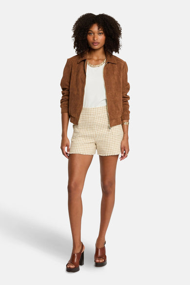 Manteau court brun de Morgan De Toi, avec une texture lisse, porté sur un haut blanc et des pantalons en tweed.