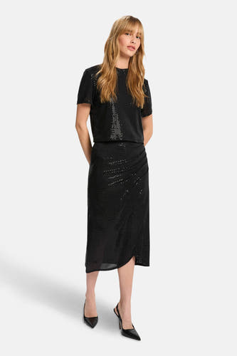 Robe noire de Morgan De Toi, avec détail de surpassement et subtiles paillettes, associée à des escarpins noirs.