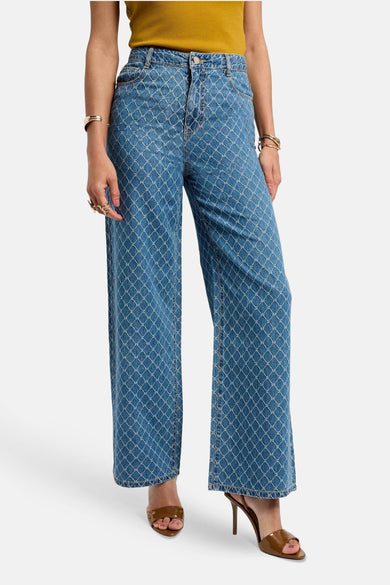 Jean bleu de Morgan De Toi, avec un motif monogrammé sur toute la surface et porté avec des bottes marron.