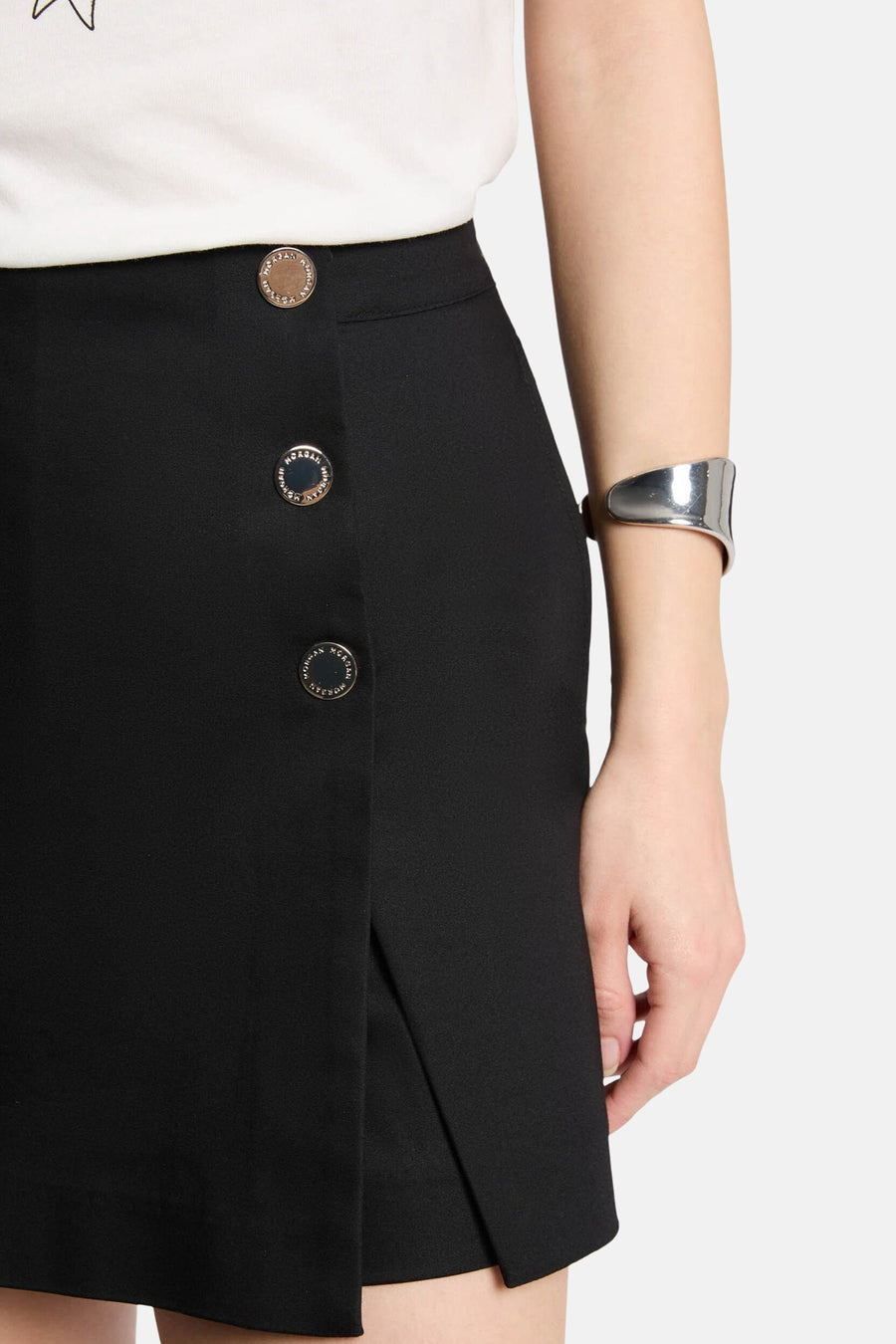 Zwarte rok met knopen en zilveren armband.
