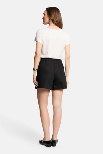 Vrouw in witte top en zwarte shorts, achteraanzicht.