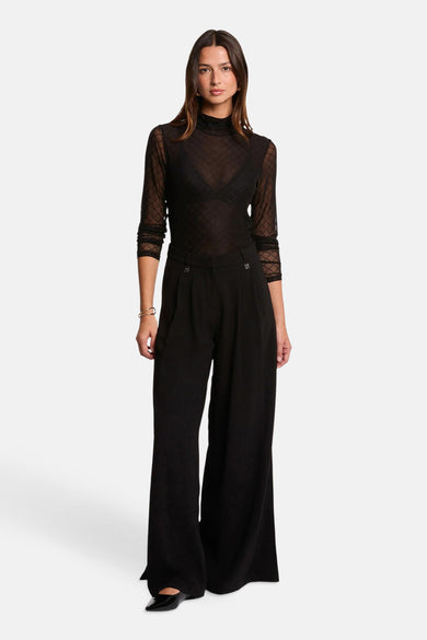 Blouse noire à longues manches de Morgan De Toi, avec un fin motif à carreaux et portée sur un soutien-gorge noir.