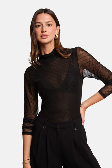 Blouse noire à longues manches de Morgan De Toi, avec un motif de lunettes, associée à un pantalon noir.
