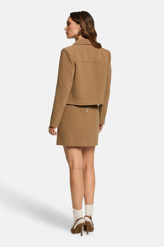 Manteau court beige de Morgan De Toi, complet avec une jupe coordonnée et des bottes brunes.