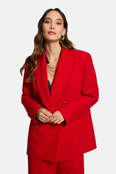 Manteau rouge de Morgan De Toi, vu de derrière, avec un pantalon à larges bretelles coordonné.