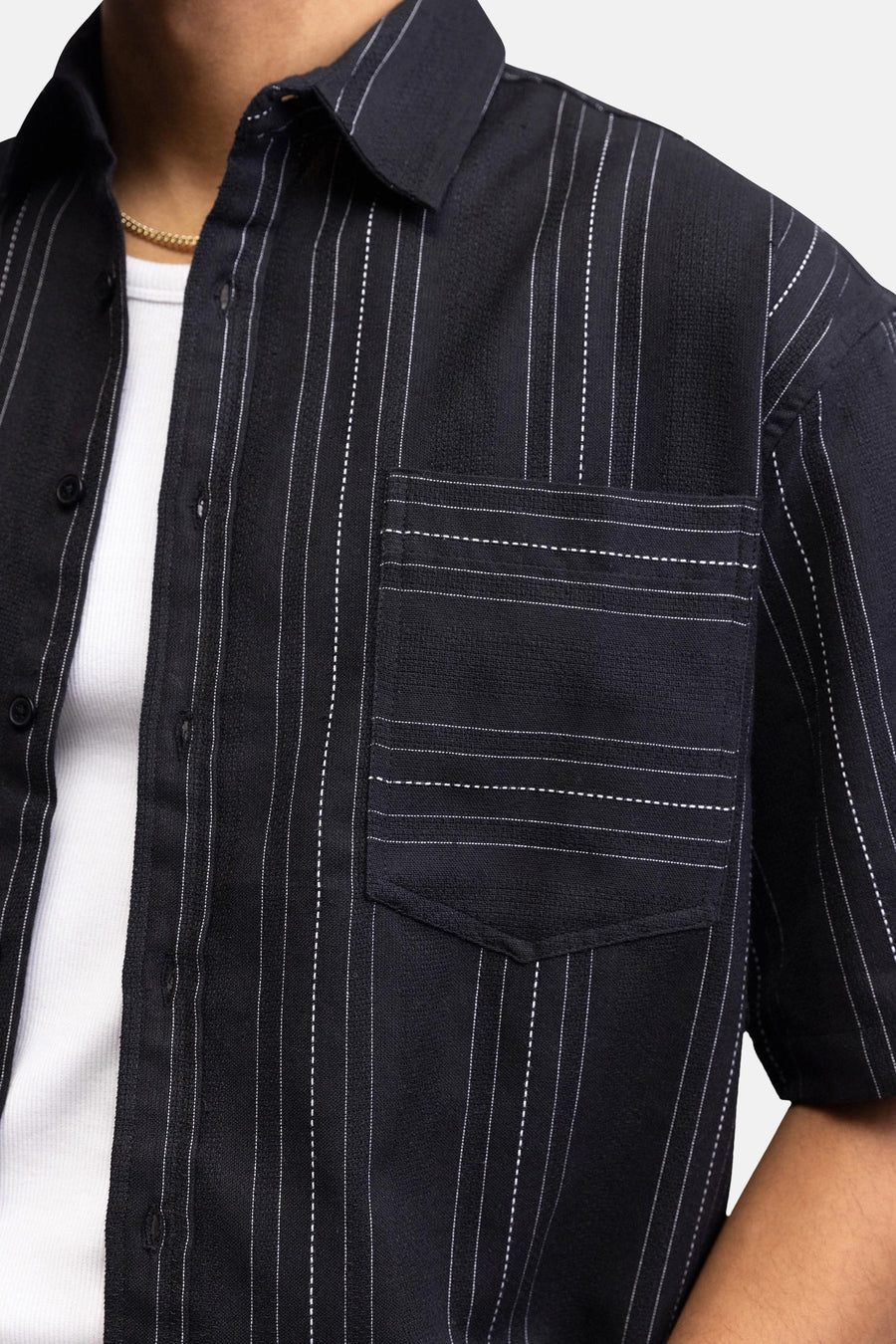 Chemise noire à manches courtes de REDEFINED REBEL, avec rayures verticales blanches, tissu texturé et poche poitrine avec surpiqûres horizontales.