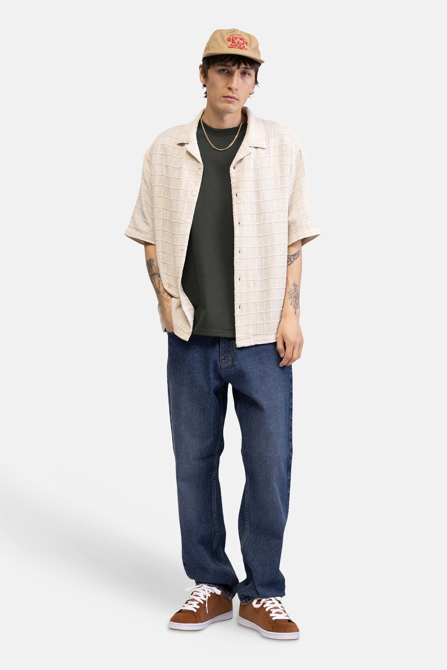 Chemise beige à manches courtes de REDEFINED REBEL, avec une texture rayée tissée, portée sur un t-shirt vert foncé.