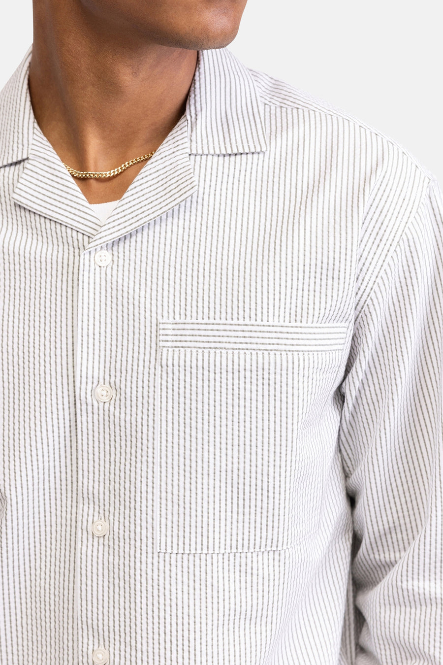 Chemise blanche à manches longues de REDEFINED REBEL, avec rayures verticales grises, col cubain, poche poitrine et chaîne dorée.
