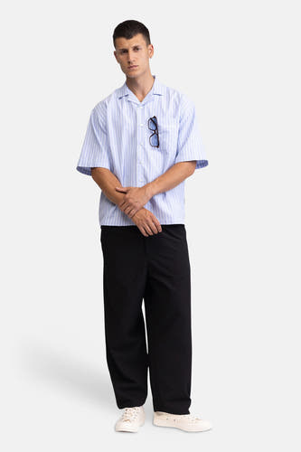Blauw gestreept korte mouwen overhemd van REDEFINED REBEL, met borstzakje en knoopsluiting, gedragen met zwarte broek en witte sneakers, front view.