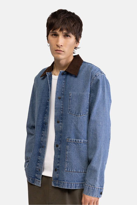 Veste en jean en denim bleu de REDEFINED REBEL, avec col marron et fermeture à boutons, portée sur un t-shirt blanc.
