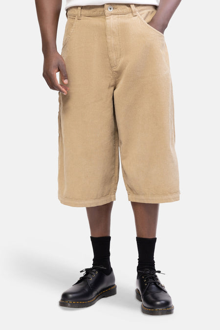 Short en velours côtelé beige de REDEFINED REBEL, vu de dos avec poches plaquées et jambes larges, porté avec des chaussettes et des chaussures noires.