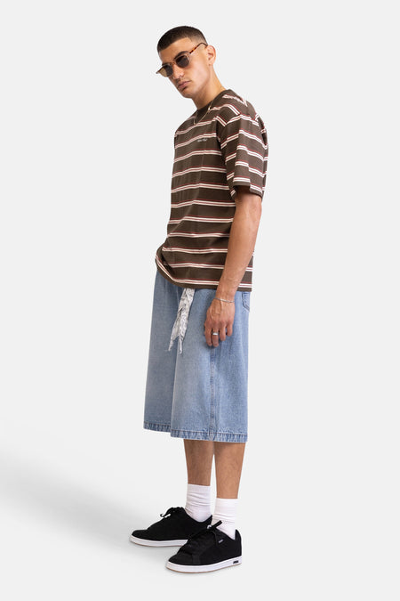 Shorts en jean clair de REDEFINED REBEL, coupe ample jusqu'au genou, portés par un mannequin avec un t-shirt rayé et un bandana.