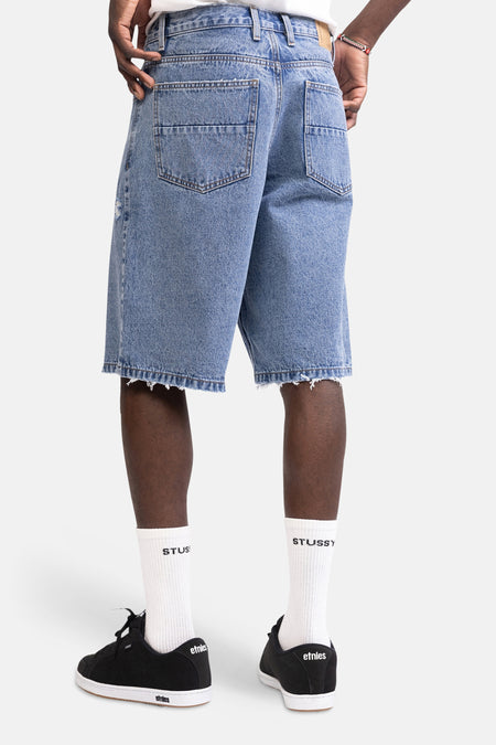 Mid-blauw denim short van REDEFINED REBEL, van achteren gezien met rafelige zomen en twee achterzakken.