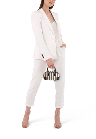 Sac à bandoulière noir de Morgan De Toi, avec des rayures verticales et des détails dorés, porté par un mannequin en tailleur-pantalon blanc.