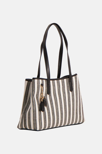 Sac à bandoulière noir de Morgan De Toi, avec un motif rayé et des anses noires, plus un pompon décoratif.