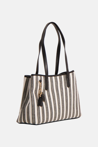 Sac à bandoulière noir de Morgan De Toi, avec un motif rayé et des anses noires, plus un pompon décoratif.