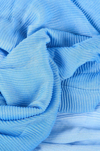 Blauwe zomersjaal van Morgan de Toi, met een glinsterende, geplooide textuur en gedrapeerde plooien.
