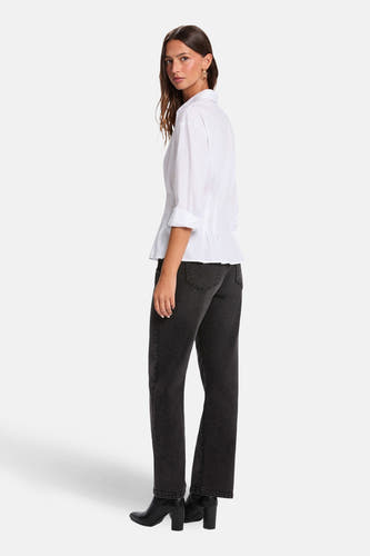 Wit overhemd met lange mouwen van Morgan De Toi, gedragen met zwarte jeans en laarzen met hak.