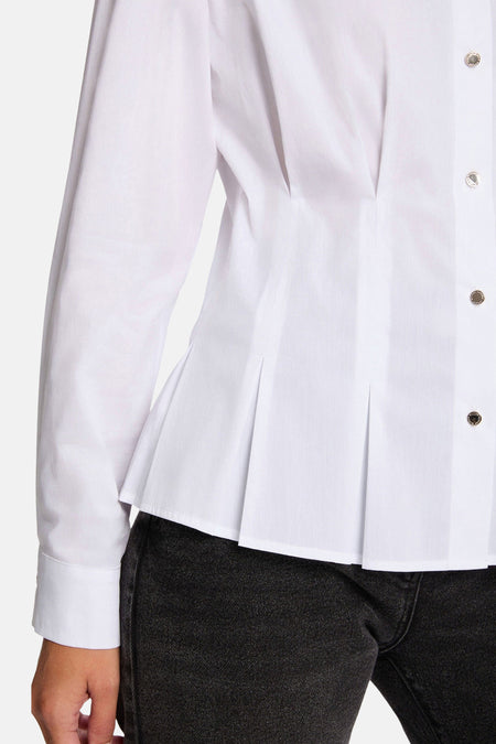 Witte blouse met peplum en zilveren knopen, zwarte spijkerbroek.
