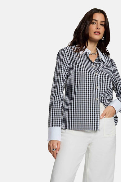 Chemise à carreaux noirs et blancs à manches longues de Morgan De Toi, avec col et poignets blancs, associée à un pantalon blanc et des talons noirs.