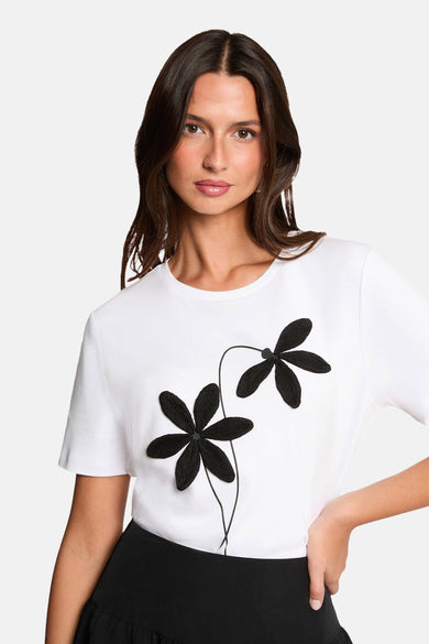 T-shirt blanc à manches courtes de Morgan De Toi, porté avec une jupe ballon noire et des talons.