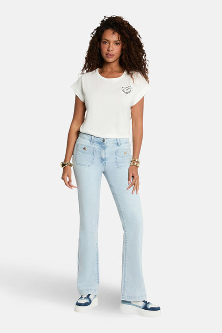 Vrouw in lichte jeans, wit shirt en sneakers.