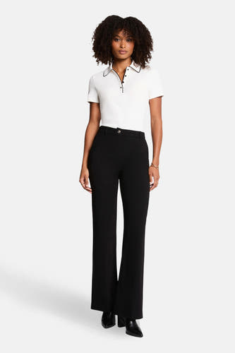 Polo blanc à manches courtes de Morgan De Toi, fini avec des bordures noires et porté avec un pantalon noir et des bottes.