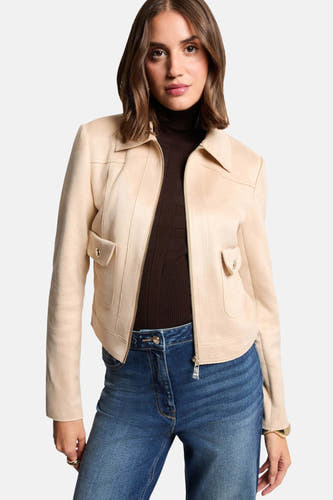 Manteau beige de Morgan de Toi, avec fermeture éclair et poche sur la poitrine, associé à un pantalon brun et des jeans.