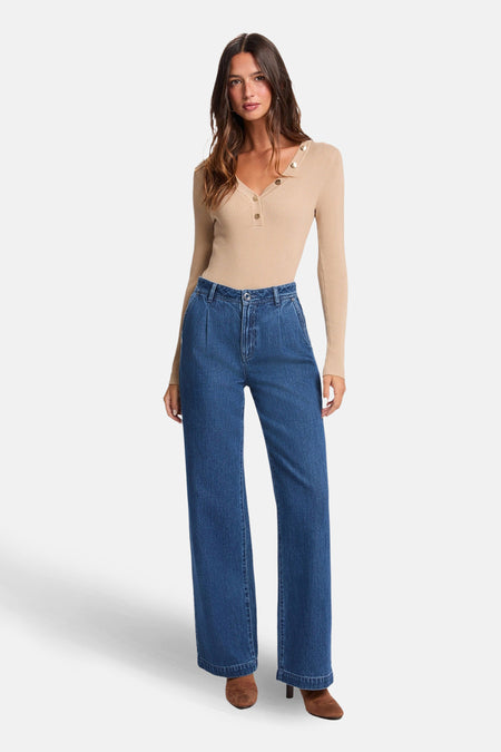 Vrouw met beige top en wijde jeans.