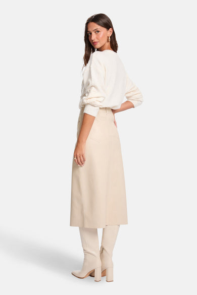 Ecrukleurige trui met ronde hals van Morgan De Toi, gedragen met een beige rok en bijpassende laarzen.